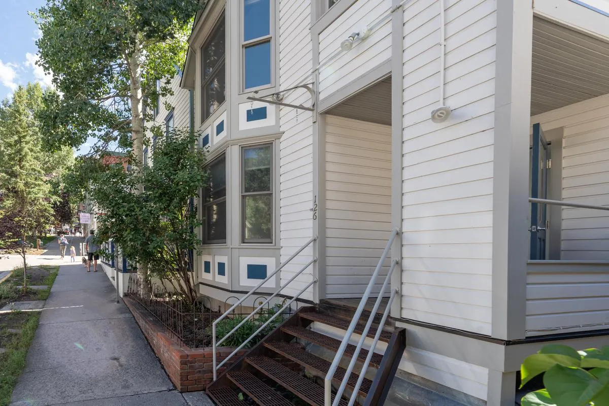 An exterior view of a property’s welcoming entrance steps, framed by large windows and surrounded by greenery. This scene suggests the immediate proximity to neighborhood life while highlighting the transition between home comfort and urban adventure.